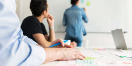 Team bei einer Planungsbesprechung, eine Kollegin schreibt Notizen an das Whiteboard