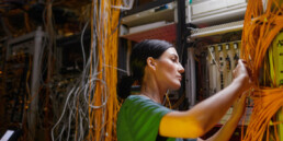 Technikerin ordnet Patchkabel in einem Netzwerkschrank