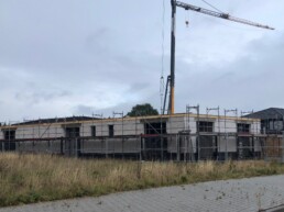 Baustelle des neuen Zenk-Firmensitzes in Kaltenkirchen: Erdgeschoss im Rohbau mit Gerüst und Baukran