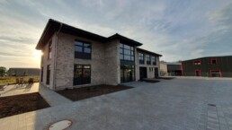 Neuer Firmensitz von Zenk Systempartner in Kaltenkirchen im Gegenlicht, Blick über den gepflasterten Hof