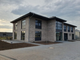 Zweigeschossiges Bürogebäude von Zenk Systempartner in Kaltenkirchen mit Klinker und dunklen Fensterrahmen